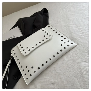 Detail of white leather clutch bag with black square studs and matching wrist strap