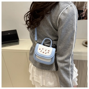 Detail of mini cherry crossbody bag in blue and white leather with top handle