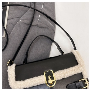 Close-up of black leather bag with plush trim detail and gold geometric lock hardware