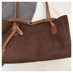 Detailed macro view of dark brown suede tote fabric and reinforced leather strap knot