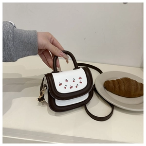 Detailed macro view of a mini PU crossbody bag featuring a cherry print and contrast design