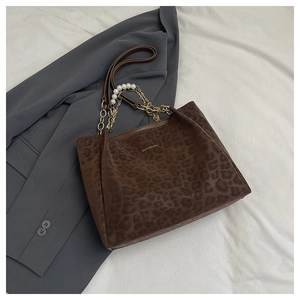 Close-up of leopard print tote bag with golden chain and elegant pearl strap details