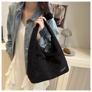 Détail du sac hobo en velours côtelé noir avec écusson doré FASHION sur le devant