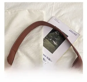 Detailed macro view of the wide brown leather shoulder strap and clean stitching