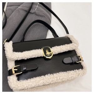 Close-up of black leather bag with white shearling trim and gold twist-lock buckle detail