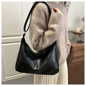 Detailed view of a vintage black PU leather crescent bag worn by a model in a cozy setting