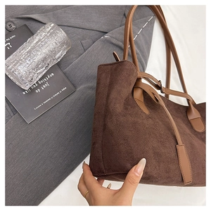 Macro detail of dark brown suede tote bag with slim leather strap and metal buckle