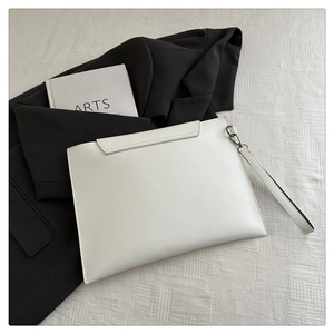 Close-up of a white envelope-style clutch bag with detachable wristlet on white fabric