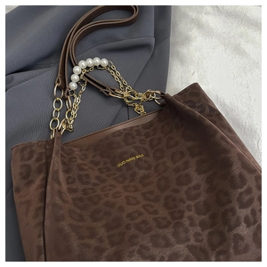 Detail of leopard print tote bag with pearl chain strap and gold hardware accents