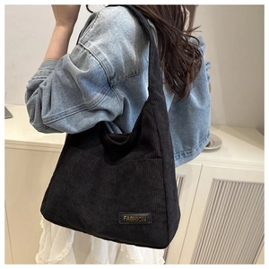 Détail du sac cabas en velours côtelé noir montrant la texture douce et l'étiquette