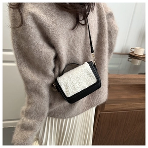 Detail view of a black leather and white fuzzy faux fur saddle bag worn by a model