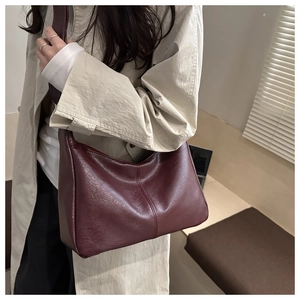 Detail of burgundy PU leather hobo bag showing natural texture and wide shoulder strap