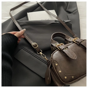Macro detail of brown retro bowling bag showing vintage PU leather texture and gold buckle