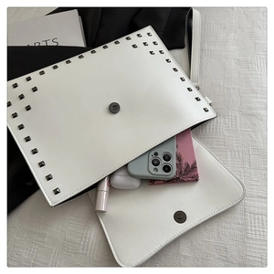 White envelope clutch with rivets showing capacity for phone, earbuds and lipstick