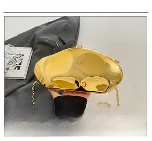 Close-up of golden irregular metal evening clutch with detachable chain strap and mirror finish
