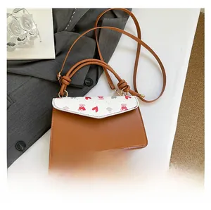 Detail of brown and white crossbody bag with cute bear print and knotted handle strap