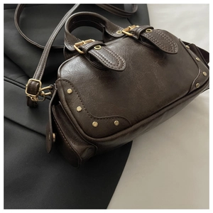 Detailed view of deep brown vintage bowling bag featuring gold rivets and shoulder strap