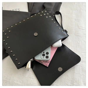 Detail of black leather chain bag with silver studs showing phone and earbud storage