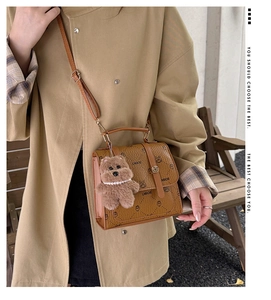 Detail of a brown LNBOE crossbody bag featuring a cute plush bear charm and cat print