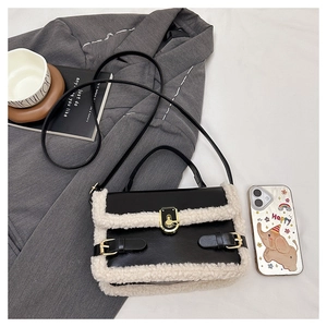 Detail of contrast patchwork handbag featuring cream fleece, black PU, and gold twist lock
