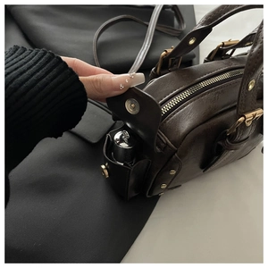 Detail of vintage brown leather handbag featuring side pocket for lipstick storage