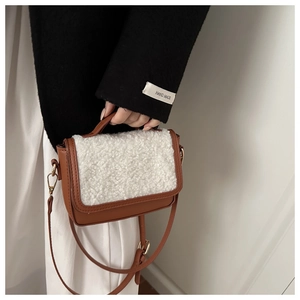 Detail showing brown leather saddle bag with white shearling flap and gold hardware