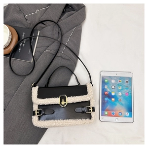 Chic black leather handbag with off-white faux fur trim and gold buckle hardware