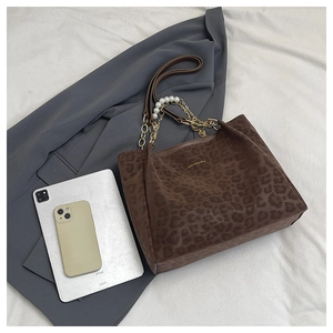 Detail of leopard print tote bag with elegant pearl chain and gold brand logo