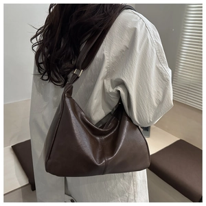 Detailed view of deep brown faux leather shoulder bag with vertical stitching and metal buckle