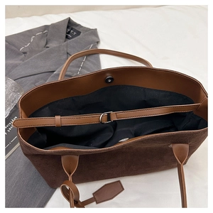 Detail view of large dark brown suede tote bag with magnetic closure and inner strap