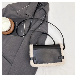 Detail of crossbody bag featuring black matte leather with ivory faux shearling trim
