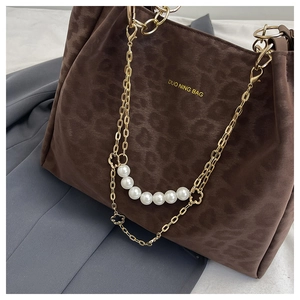 Detail of leopard print suede bag with gold chain and decorative pearl floral charm