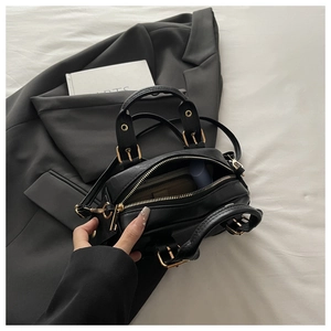 Detail of black bowling bag showing multi-compartment interior and gold hardware details
