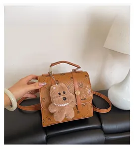 Close-up of a brown LNBOE backpack featuring printed patterns and a cute plush bear charm