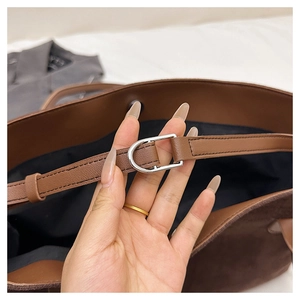 Detail of silver hardware D-ring and strap connection on dark brown leather tote