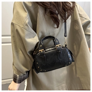Close-up of black leather crossbody bag with gold rivets and adjustable shoulder strap