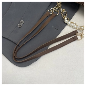 Detail of a brown leather bag strap with elegant pearl and golden clover charm decoration