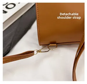 Detail of a brown leather backpack with golden metal hook and detachable strap