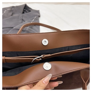 Detail view of magnetic silver clasp and interior lining of brown suede tote bag