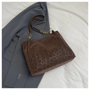 Detailed macro view of leopard print tote bag with brown leather straps and gold chain hooks