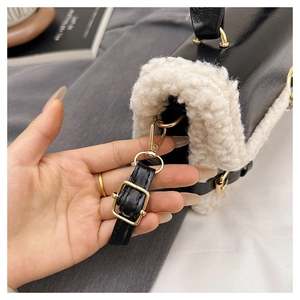 Detail of golden metal hook and black leather strap on plush patchwork shoulder bag