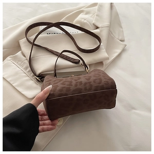 Close-up of leopard print cylindrical bag with suede texture and metal buckle detail