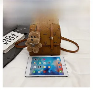 Brown pebbled leather handbag size comparison with a tablet and plush bear charm
