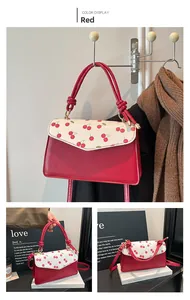 Detail of red PU leather shoulder bag with cherry print and matching slim strap