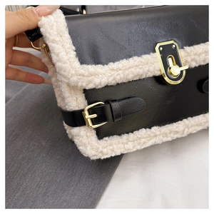 Close-up of black leather handbag with beige faux shearling trim and golden metal lock