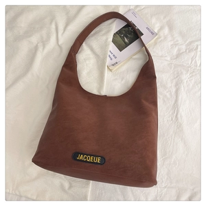 Detail view of a retro dark brown leather tote bag with brand label on white fabric