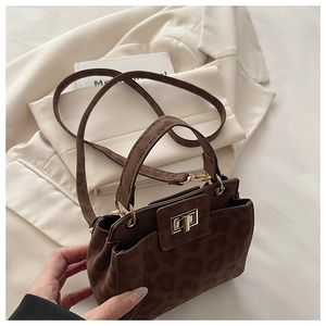 Detail of leopard print handbag with gold twist lock on beige blazer background