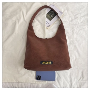 Detail view of large tote bag with brand label and phone for size comparison