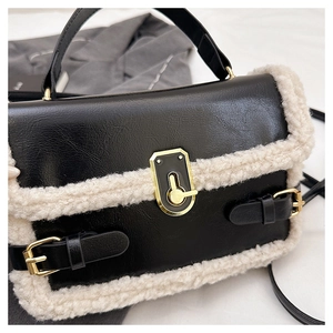 Detailed view of black PU leather shoulder bag with white faux shearling and gold twist lock