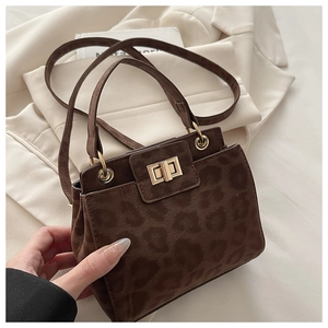Detail of leopard print suede handbag with gold turn-lock closure and shoulder strap